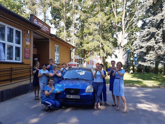 Pracownicy GOPSu wokół samochodu udekorowanego motylami